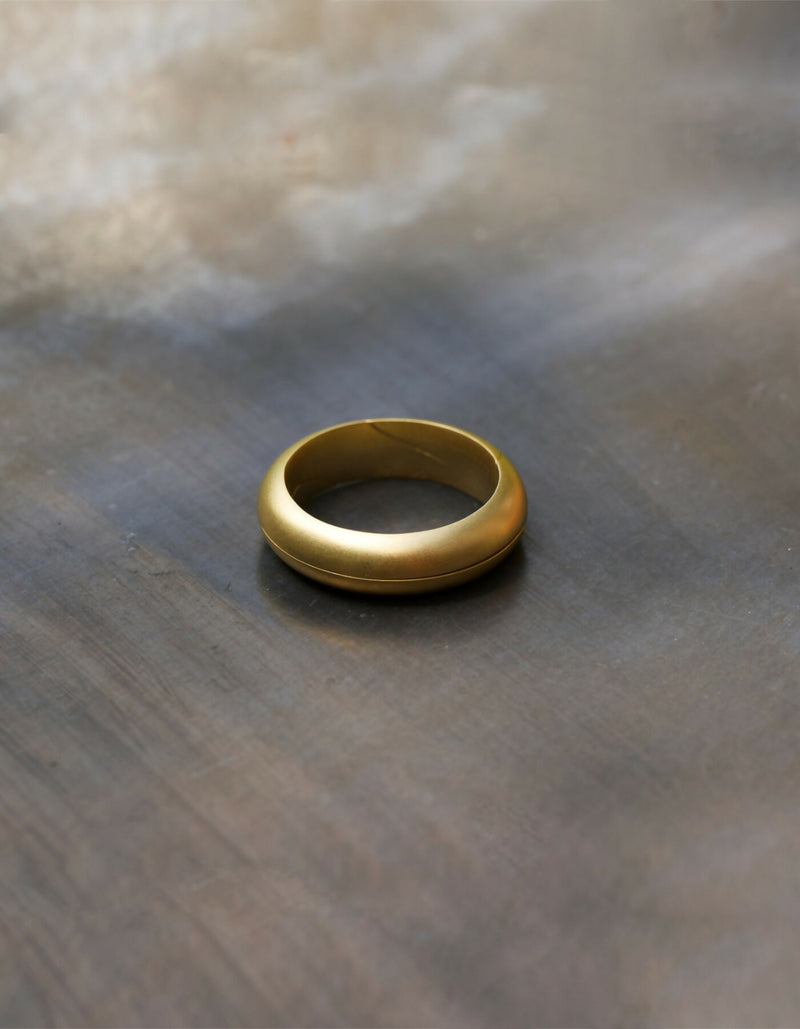 Two-piece ring made of gold with a matt surface, lying down, viewed diagonally from above