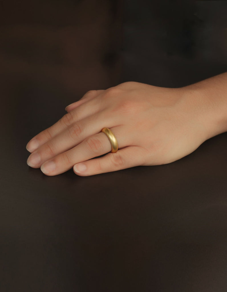 Two-piece ring made of gold with a matt surface, worn on the ring finger of the left hand.