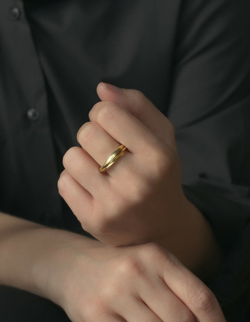 Two-piece gold ring with a polished surface, worn on the middle finger of the left hand.