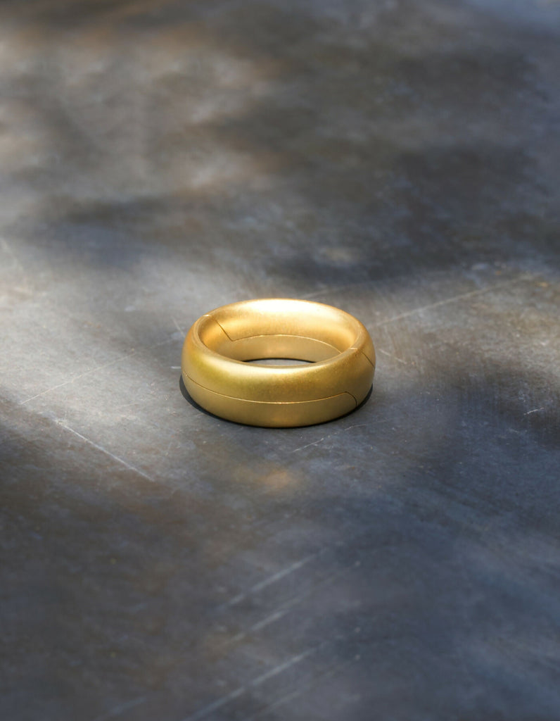 Two-piece gold ring with a matt surface and an oval cross-sectional profile, lying flat when closed