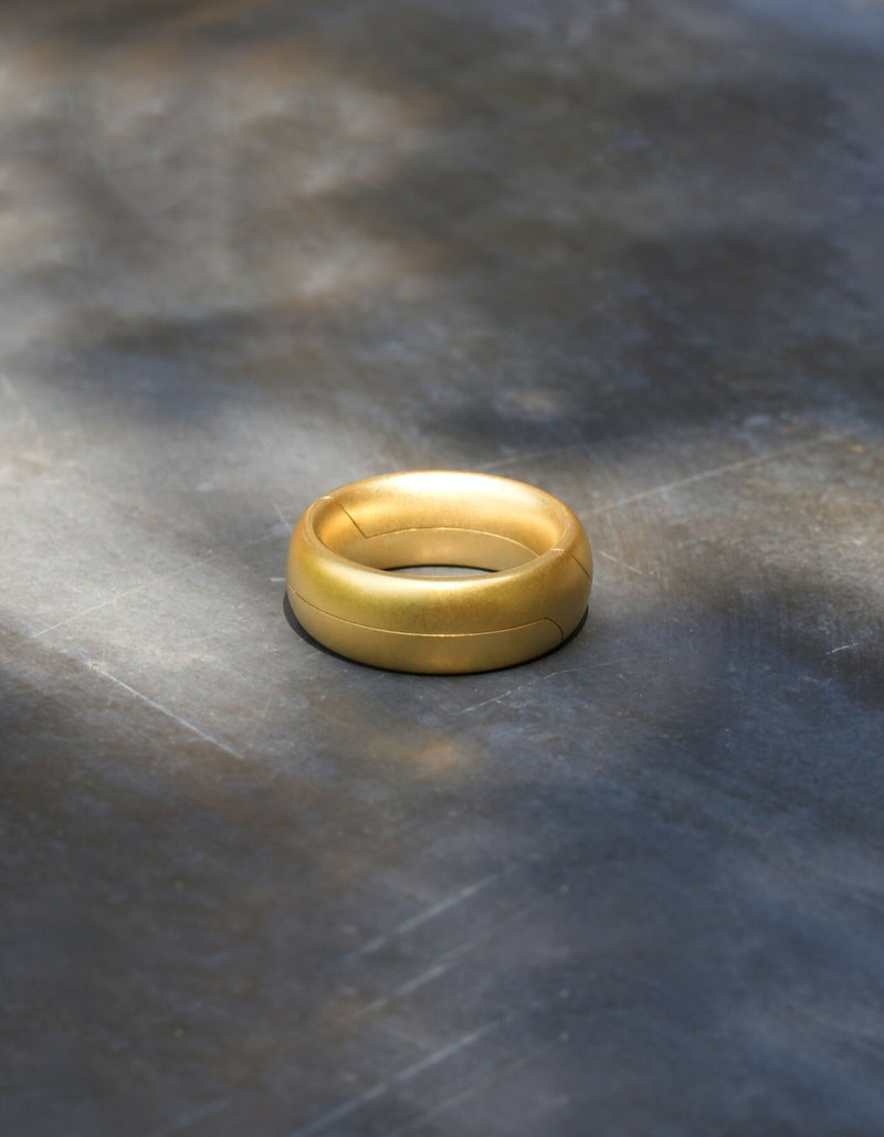 Two-piece gold ring with a matt surface and an oval cross-sectional profile, lying flat when closed