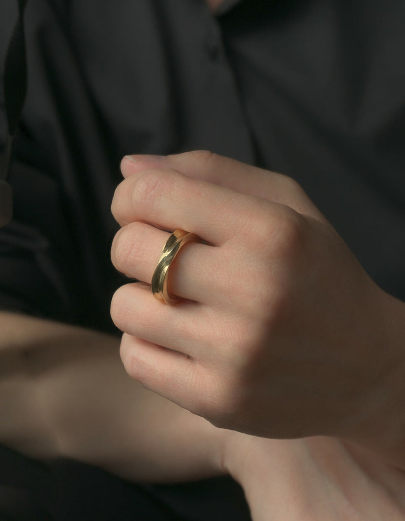 Two-piece gold ring with a polished surface, worn on the middle finger of the left hand