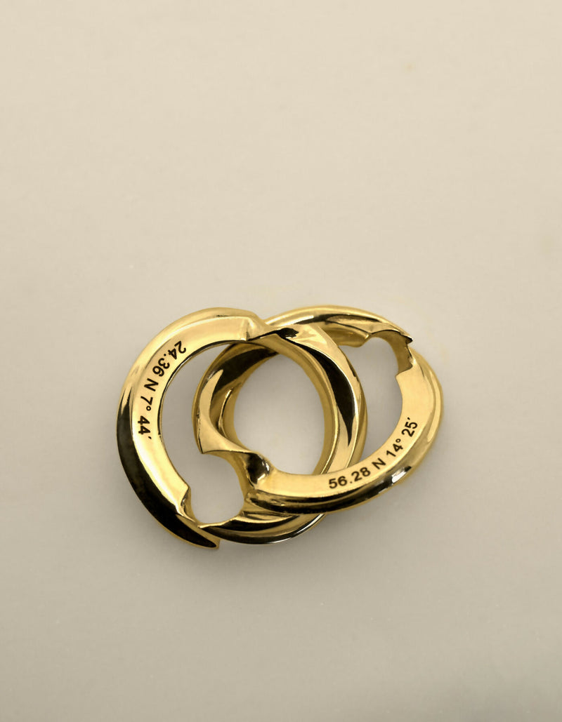 Two-piece gold ring with a polished surface, the ring lies open so that both hidden inner sides with the individual engraving can be seen