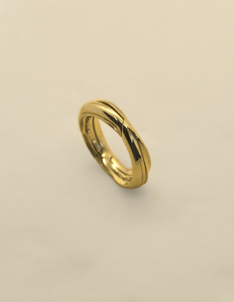 Two-piece gold ring with polished surface, standing upright, viewed diagonally from the front