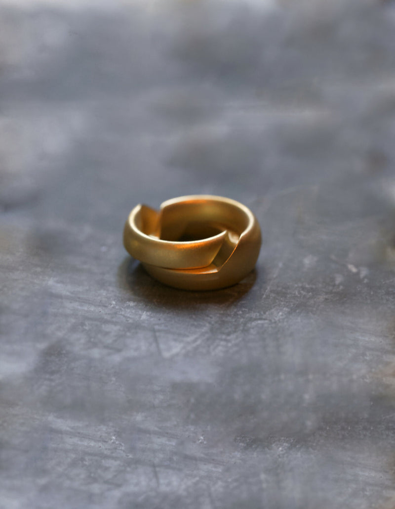 Two-part gold ring with a matt surface and an oval cross-sectional profile, slightly open, the two halves are slightly offset from one another. The hidden inner surfaces offer space for individual engraving