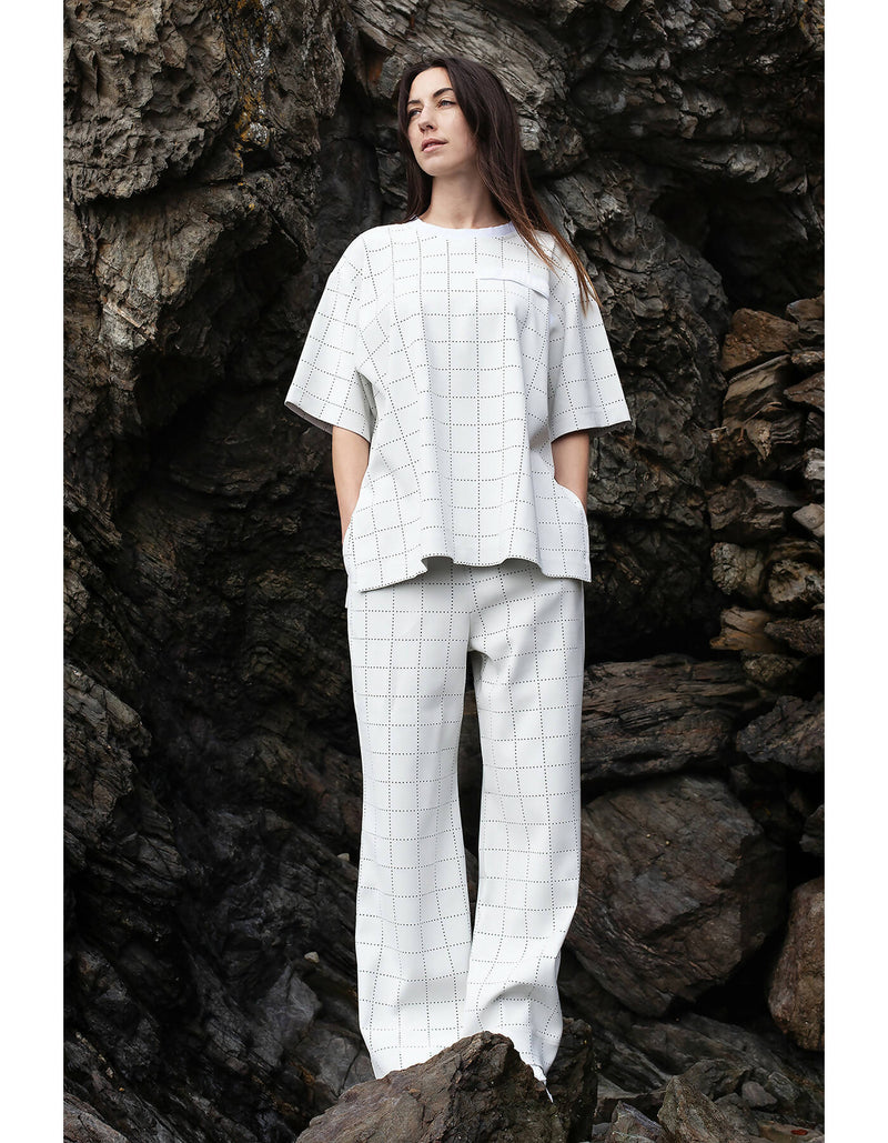 Romane is wearing White Canvas sustainable light grey color, genderless, seasonless casual checks trousers, size S. The Essential checks trousers have minimal modern aesthetics design allowing comfort and bringing self-confidence. This unique piece is made locally in Paris to reduce environmental impact and guarantee high quality and durability of the products.